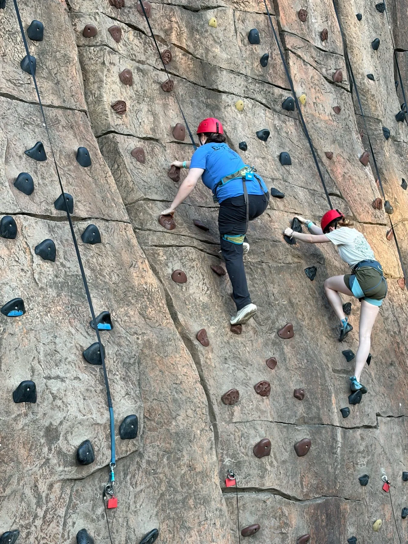 Two Scouts climbing a tall rock wall